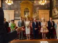 Le couple se tient au centre, entouré de leurs 5 témoins mariage. La mariée porte une robe blanche et tient un bouquet. Les invités sont élégamment vêtus.