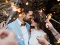Un couple s'embrasse tendrement, entouré de feux de Bengale, lors de leur entrée pour une cérémonie laïque joyeuse.