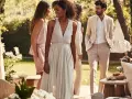 Des invités élégants discutent lors d'un brunch de mariage en plein air. Idées pour comment s'habiller pour un brunch de mariage : robes légères et costumes clairs.