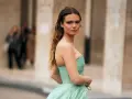Une jeune femme en robe bustier vert menthe, parfaite pour savoir comment s'habiller pour un mariage. Cheveux longs ondulés, maquillage audacieux.
