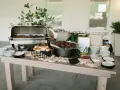Buffet de brunch mariage avec plats chauds, petits pains, garnitures et assiettes empilées.