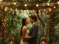 Un couple s'embrasse tendrement sous une arche décorée de guirlandes lumineuses, un doux moment de mariage en forêt.