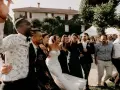 Un groupe d'amis danse joyeusement, la mariée en robe blanche au milieu. Une scène de mariage pleine de vie, avec une ambiance de parole chanson mariage rigolote.