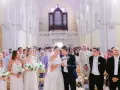 Mariage dans une église : la mariée et le marié lisent un texte, entourés des invités et des demoiselles d'honneur.
