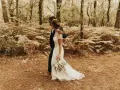 Un couple se promène dans une forêt, la mariée porte une robe blanche et tient un bouquet. Une scène de formalité mariage en pleine nature.