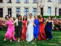 Un groupe de femmes rit joyeusement devant un château. La mariée en blanc est entourée de ses demoiselles d'honneur en robes colorées. La différence entre témoin et demoiselle d'honneur est subtile, mais leur complicité est évidente.