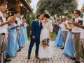 Un couple s'embrasse lors de leur petit mariage de 20 personnes. Les invités, en tenues bleues et blanches, applaudissent joyeusement.
