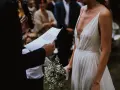 La mariée en robe blanche, bouquet à la main, écoute les vœux lors de son mariage religieux.