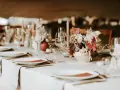 Un plan de table mariage élégant : vaisselle, verres, bougies et un bouquet de fleurs sur une table dressée.