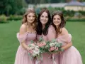 Trois demoiselles d'honneur souriantes en robes roses, tenant des bouquets de fleurs. Une belle scène pour une demande demoiselle d'honneur.