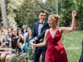 Un couple rayonnant danse lors d'un cortege mariage en plein air. La foule applaudit et filme ce moment joyeux.