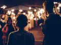 Couple au milieu d'une foule tenant des feux de Bengale, ambiance magique pour ce mariage sans dj.