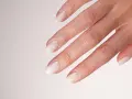Main d'une mariée avec un french manucure spécial mariage, aux ongles laqués d'un blanc nacré, prêts pour le grand jour.
