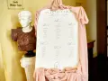 Plan de table de mariage, avec la disposition des invités par table. Une statue antique et des drapés roses décorent l'entrée.