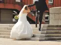 Un couple s'enfuit sur des escaliers après leur cérémonie de mariage. La mariée porte une robe blanche et un voile, tenant un bouquet.