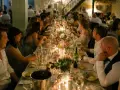 Un dîner de mariage réussi, avec une longue table dressée, des bougies, des fleurs et des invités souriants.