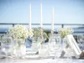 Décoration de mariage : bougies, fleurs et verres sur une table. La distance entre 2 tables mariage est suggérée par l'agencement.