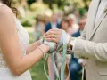 Mains jointes, rubans pastel noués, symbole d'un rituel d'union. Le couple célèbre son amour.