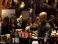 Un barman sert du vin lors d'un vin d'honneur pour 100 personnes. Des bouteilles et des verres sont disposés sur le comptoir.