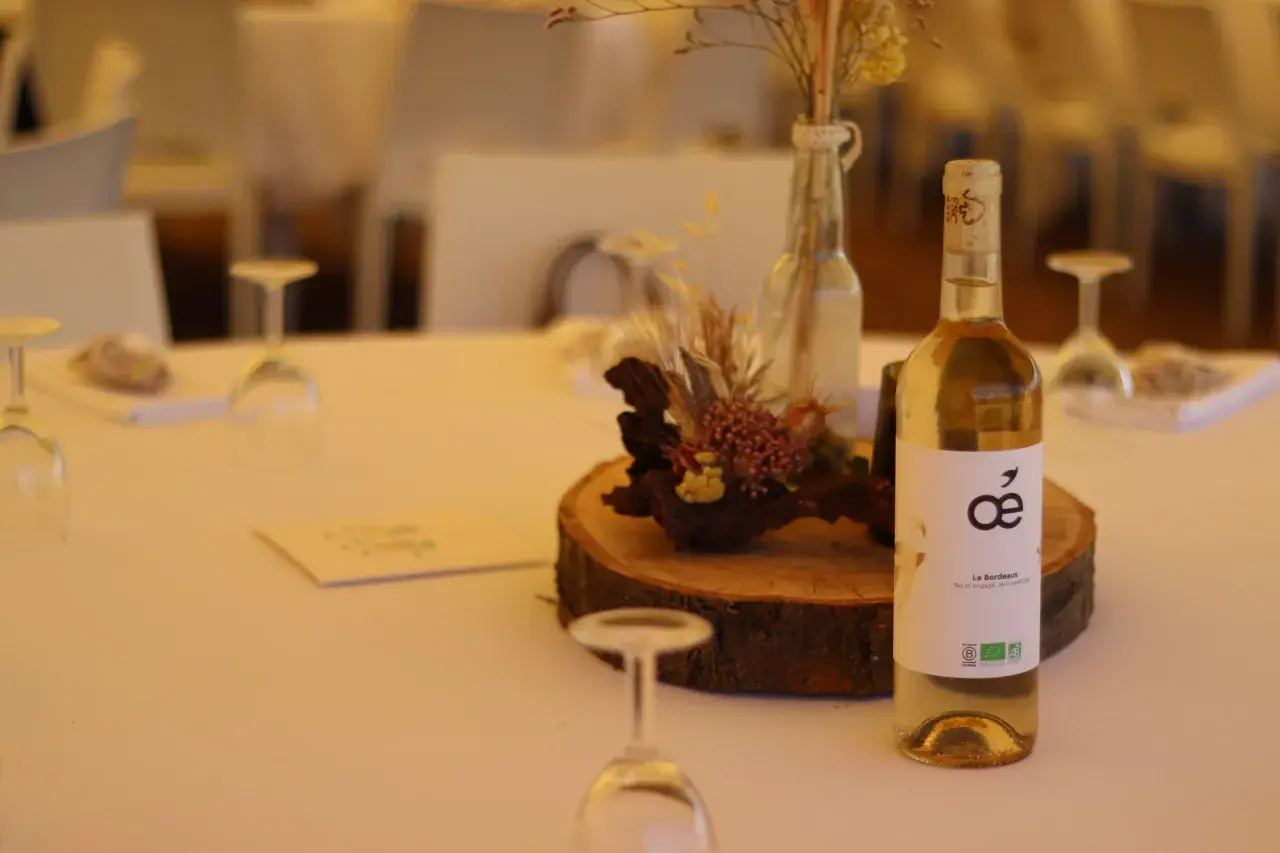 Bouteille de vin blanc sur une table de mariage, avec une décoration florale et des verres. La quantité d'alcool fort est modérée pour célébrer.