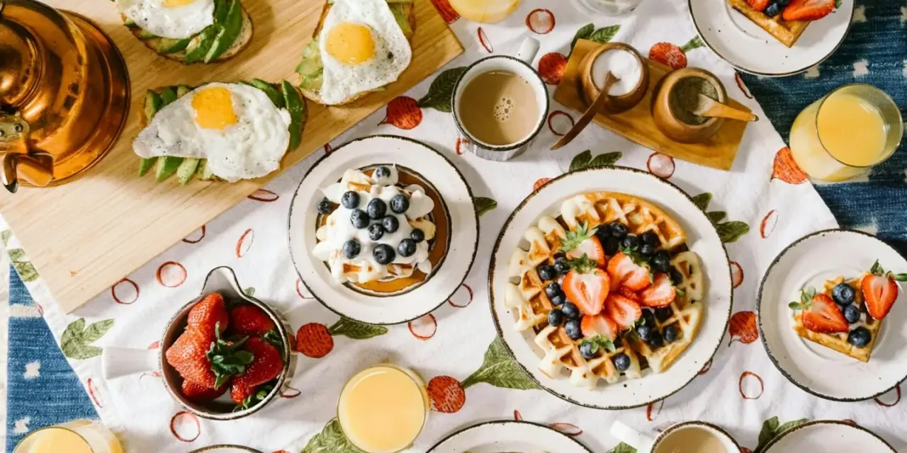 Un délicieux brunch de mariage : gaufres aux fruits, toasts avocat-œuf, jus d'orange et café. Une idée parfaite pour célébrer !