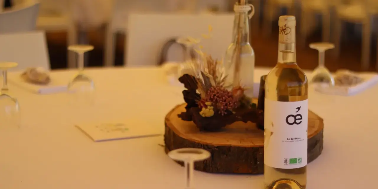 Bouteille de vin blanc sur une table de mariage, avec une décoration florale et des verres. La quantité d'alcool fort est modérée pour célébrer.