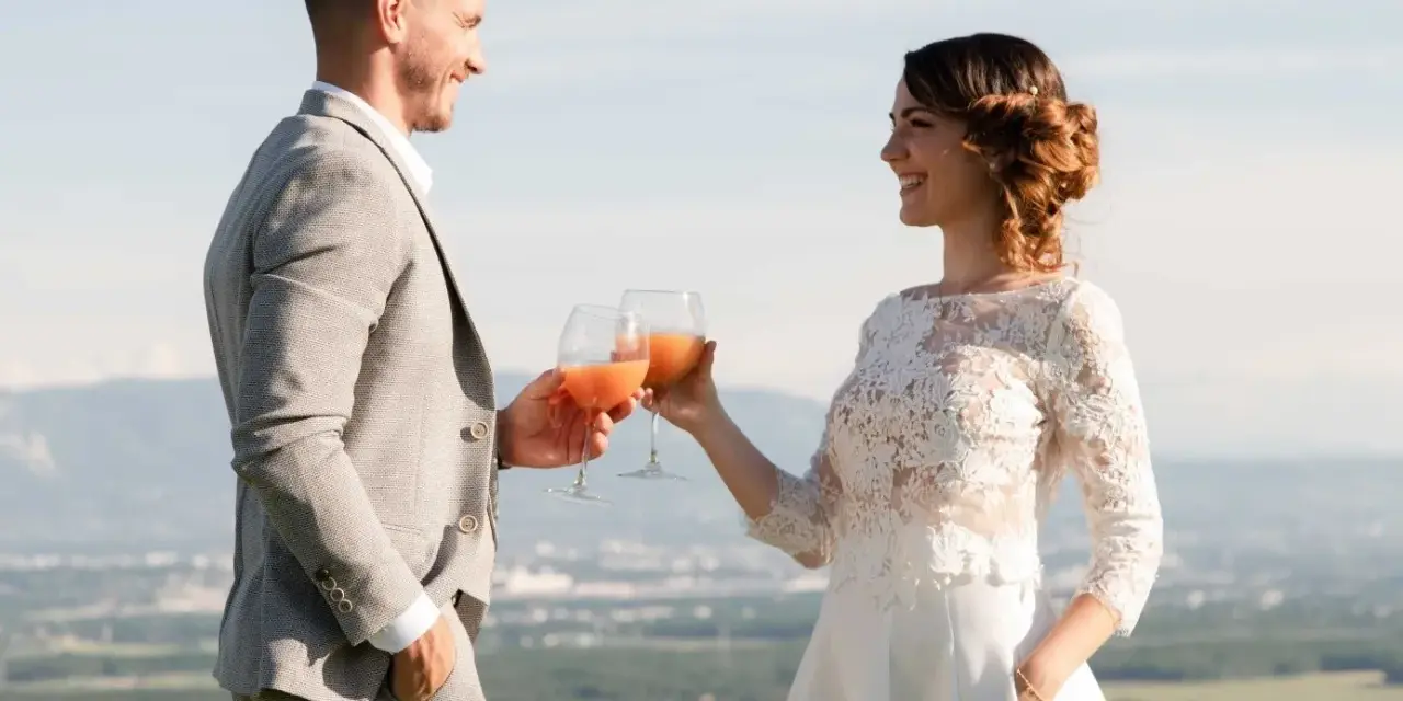 Un couple marié trinque avec des cocktails fruités, une belle quantité de soft pour un mariage en plein air.