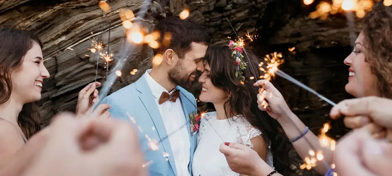 Un couple s'embrasse tendrement, entouré de feux de Bengale, lors de leur entrée pour une cérémonie laïque joyeuse.