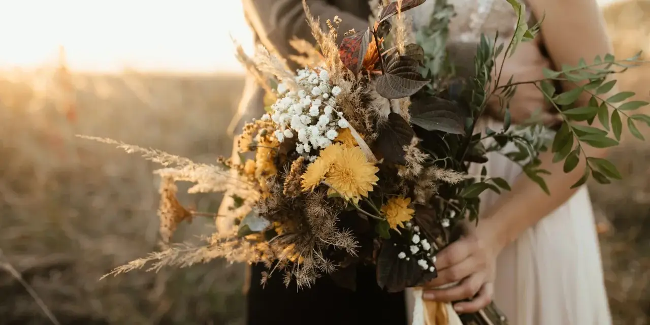 Un bouquet champêtre aux tons chauds, parfait pour des cadeaux invités mariage fait maison. Des herbes de la pampa, des fleurs jaunes et des feuilles sombres.