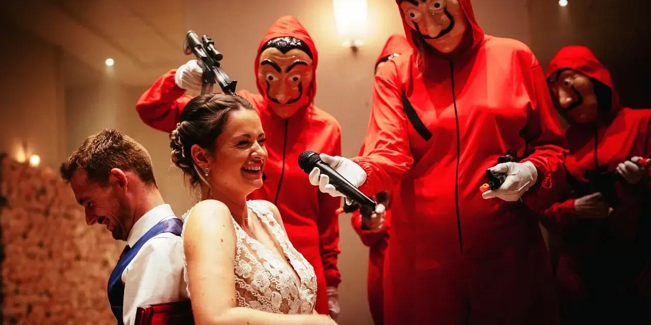 Une mariée hilare, un micro tendu par un personnage masqué rouge. Une scène inattendue pour un mariage surprise.