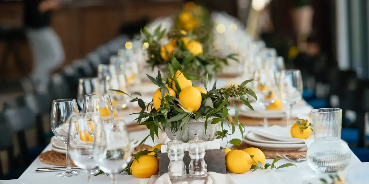 Un élégant nom de table mariage orné de citrons frais et de verdure. Les verres à vin et les assiettes sont dressés, prêts pour un festin ensoleillé.