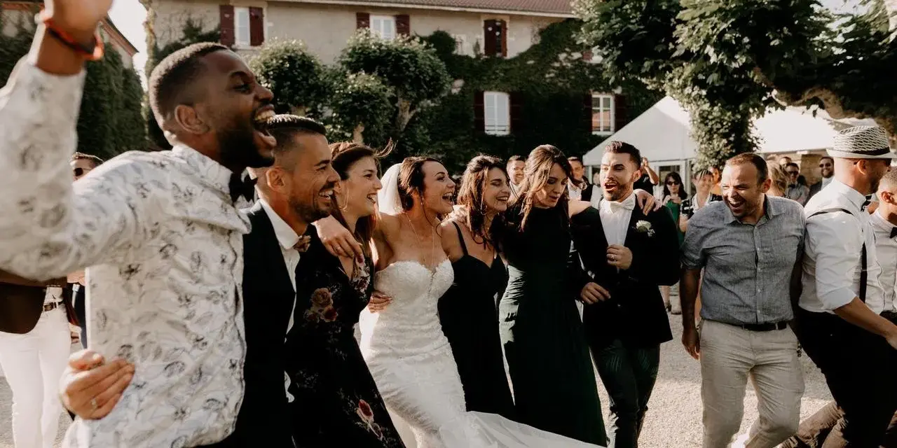 Un groupe d'amis danse joyeusement, la mariée en robe blanche au milieu. Une scène de mariage pleine de vie, avec une ambiance de parole chanson mariage rigolote.