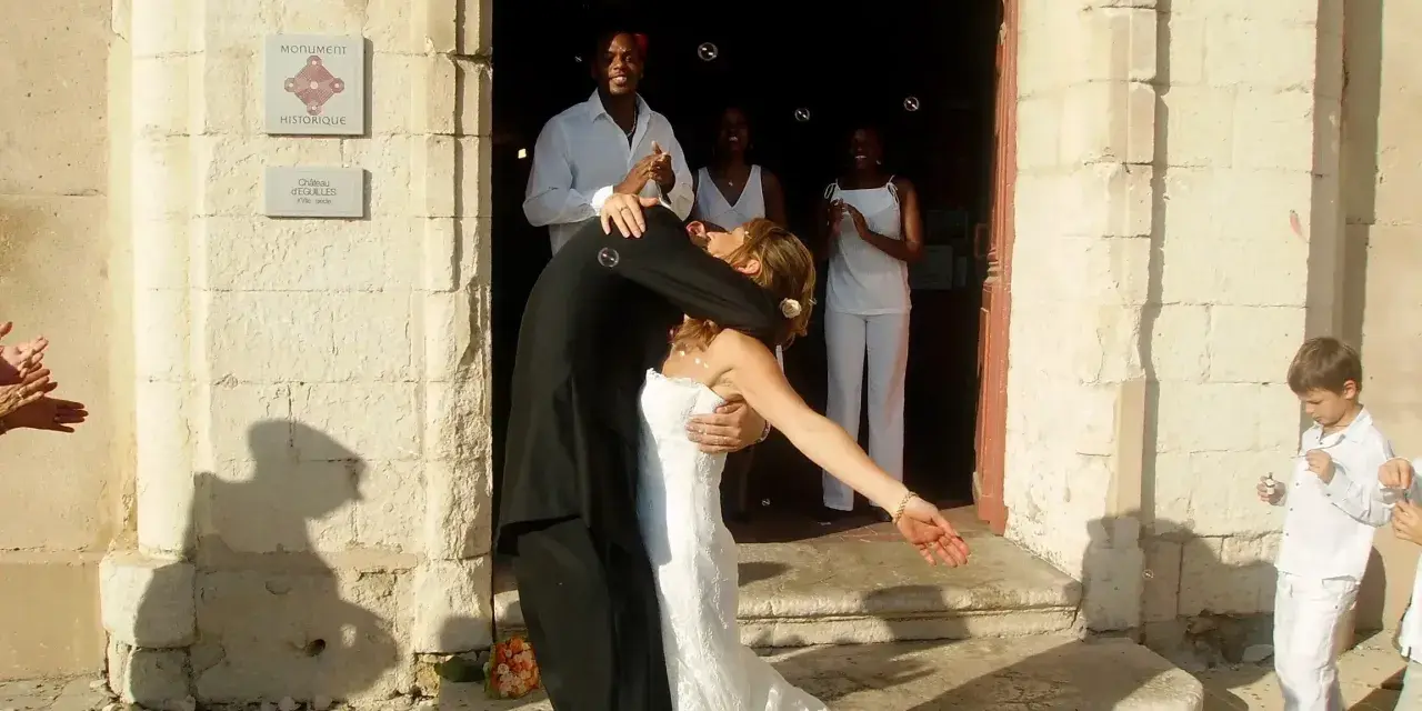 Mariage à l'église : le couple s'embrasse devant l'édifice, entouré d'invités joyeux. La musique du mariage résonne.
