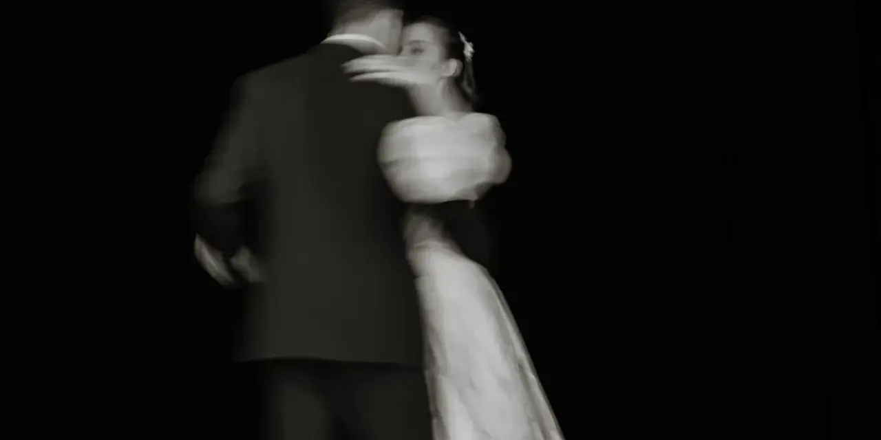 Un couple danse lors de l'ouverture de bal de leur mariage, le mouvement capturé dans un flou artistique.