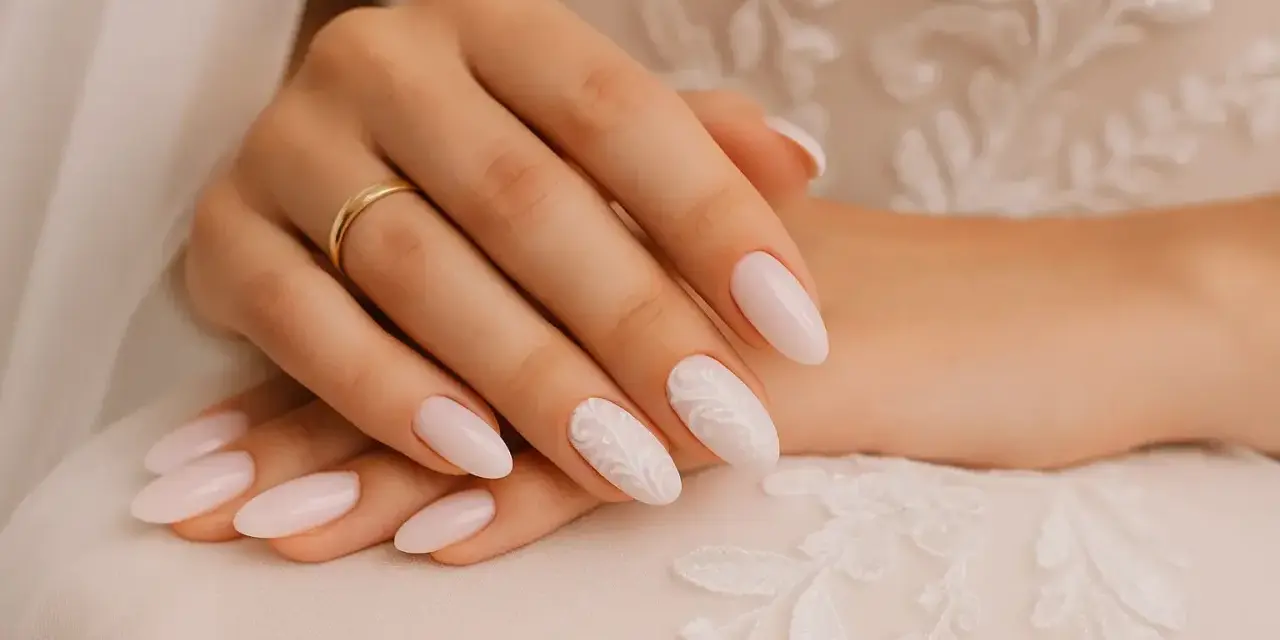 Mains d'une mariée avec des ongles tendance, ornés d'une bague dorée et d'un motif floral délicat sur un ongle.
