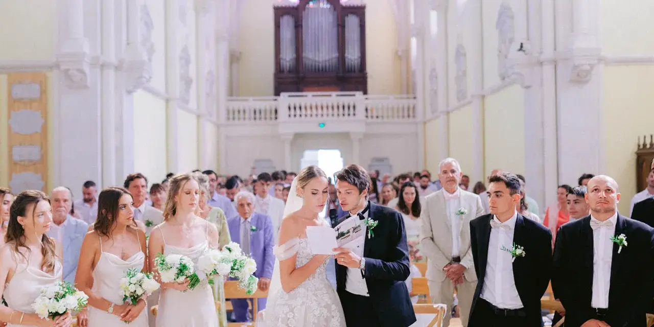 Mariage dans une église : la mariée et le marié lisent un texte, entourés des invités et des demoiselles d'honneur.