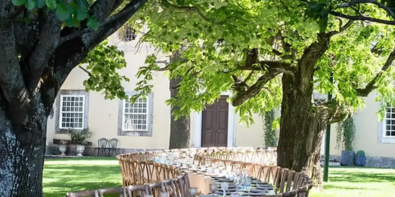 Table dressée dans un jardin luxuriant pour un quinta mariage Portugal. Ambiance champêtre sous les arbres.