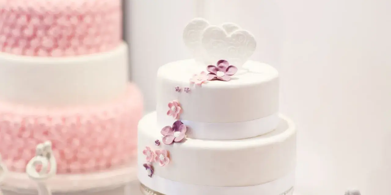 Deux pièces montées, l'une blanche décorée de cœurs et fleurs, l'autre rose texturée. Le coût d'une pièce montée peut varier.