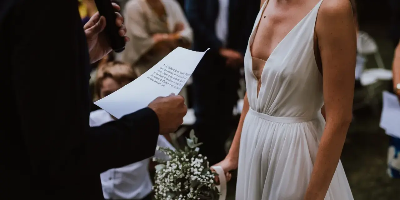 La mariée en robe blanche, bouquet à la main, écoute les vœux lors de son mariage religieux.