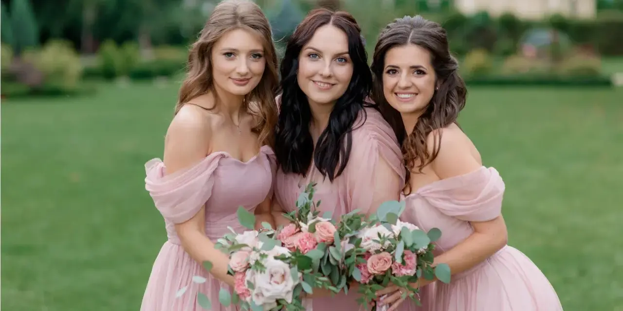 Trois demoiselles d'honneur souriantes en robes roses, tenant des bouquets de fleurs. Une belle scène pour une demande demoiselle d'honneur.