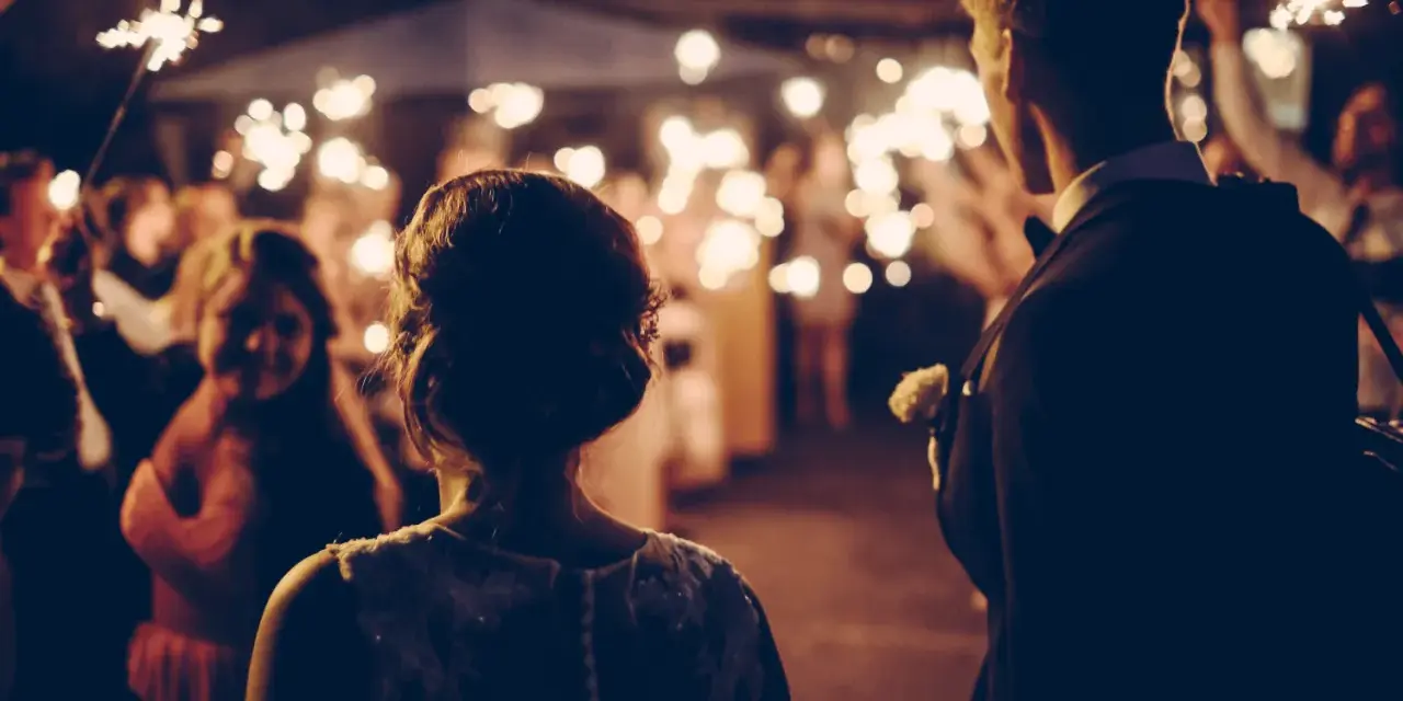 Couple au milieu d'une foule tenant des feux de Bengale, ambiance magique pour ce mariage sans dj.