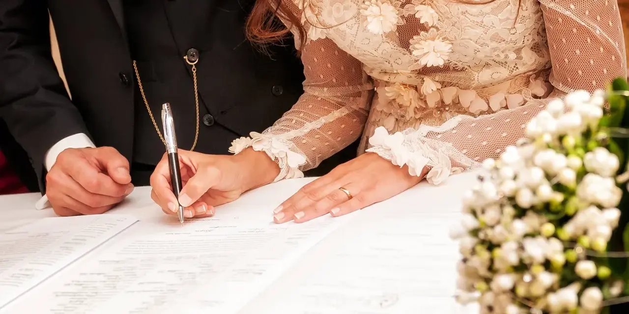 La mariée signe l'acte de mariage, un moment clé de la tradition mariage français. La bague au doigt symbolise leur union.