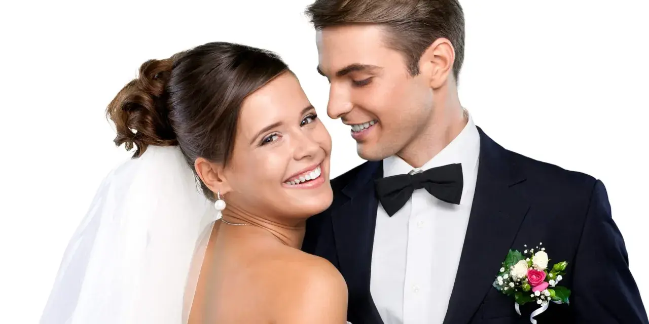 Un jeune couple marié, souriant et complice. La mariée, voile sur la tête, et le marié, nœud papillon, se préparent pour la fête. Combien donner à un mariage cousin ?