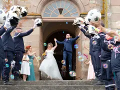 Mariés sortant de l'église sous une haie d'honneur mariage de pompiers lançant des bulles.