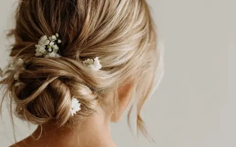 Coiffure invitée mariage boheme : un chignon flou orné de petites fleurs blanches, parfait pour une allure romantique et décontractée.