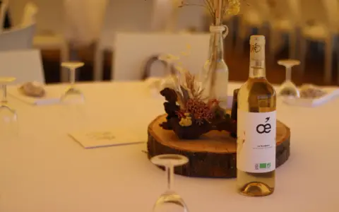 Bouteille de vin blanc sur une table de mariage, avec une décoration florale et des verres. La quantité d'alcool fort est modérée pour célébrer.