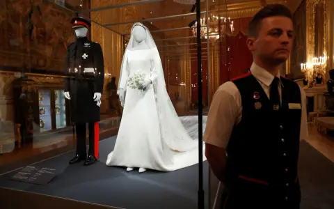 La robe mariée Meghan Markle, d'une élégance intemporelle, est exposée aux côtés de l'uniforme du Prince Harry.