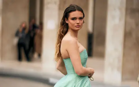 Une jeune femme en robe bustier vert menthe, parfaite pour savoir comment s'habiller pour un mariage. Cheveux longs ondulés, maquillage audacieux.