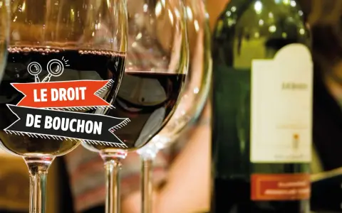 Verres de vin rouge, une bouteille et une bannière "Le Droit de Bouchon". Le prix est une question à explorer.