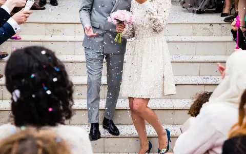 Un couple célèbre sa **danse mariage facile** sous une pluie de confettis. La mariée porte une robe blanche ornée, le marié un costume gris.